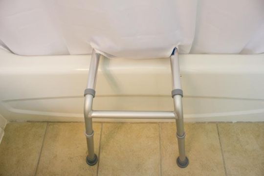 The legs of the HydroGlyde Sliding Tub Transfer Bench are shown when the shower curtain is fully closed